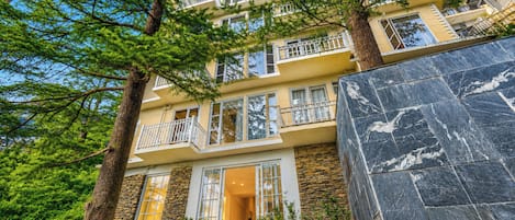 A multi-story building with balconies, a stone facade, and a well-maintained lawn.