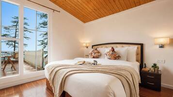 Un dormitorio con una cama grande, una mesita de noche, una lámpara y vistas al exterior a través de una puerta corrediza.