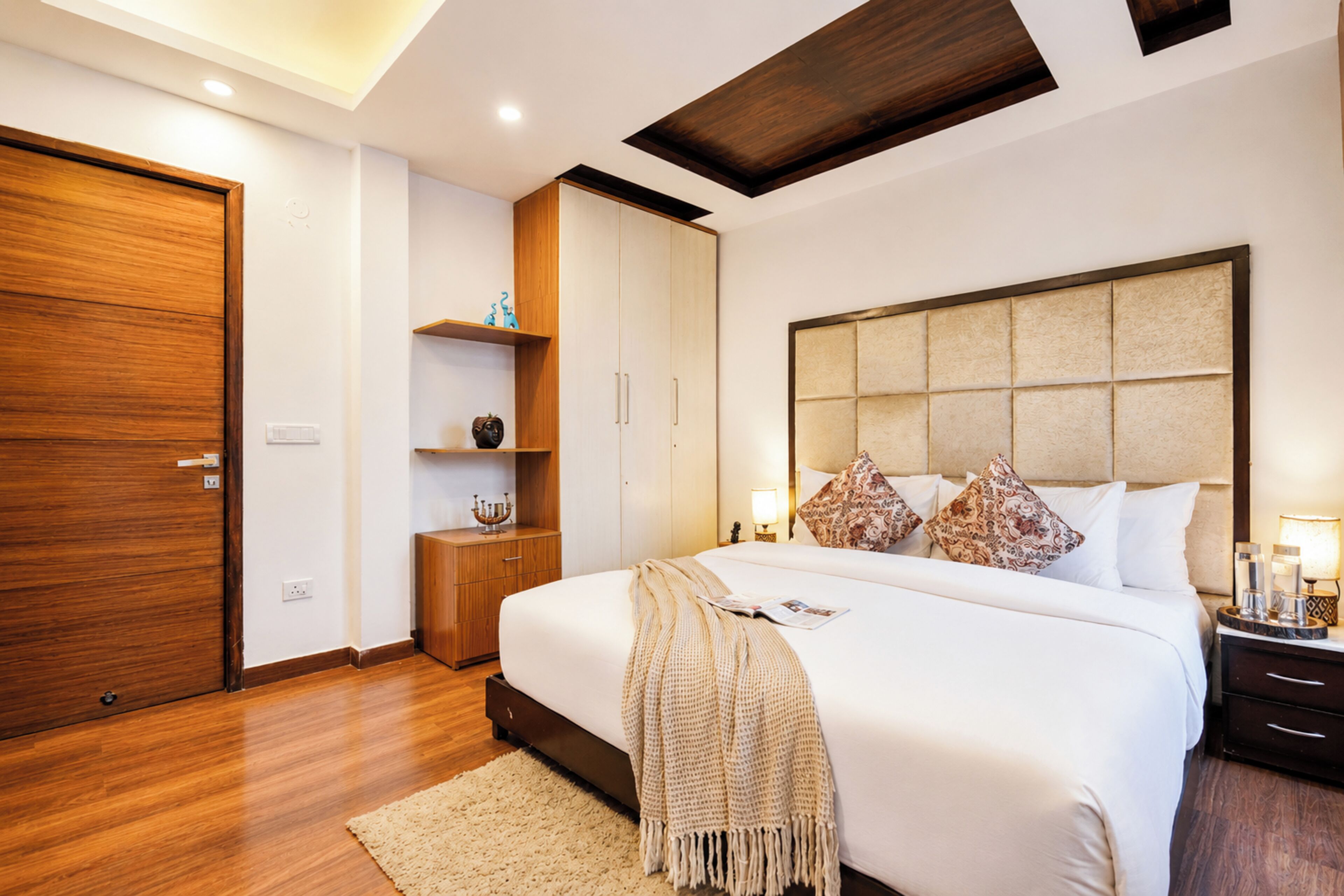 Ein modernes Schlafzimmer mit einem großen Bett, einem Holzschrank und eingebauten Regalen.