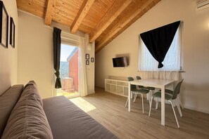 A room with a wooden ceiling, a sofa, a dining table with chairs, a TV, and a window with curtains. - [Il Parco Apartment 7] Natura & Relax-RoadTo5Terre (Beverino)