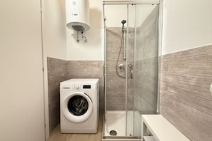 A modern bathroom with a glass-enclosed shower, a built-in washing machine, and a wall-mounted sink. - [Il Parco Apartment 7] Natura & Relax-RoadTo5Terre (Beverino)