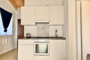 A compact kitchen with white cabinetry, a built-in oven, and a stainless steel kettle on the countertop. - [Il Parco Apartment 7] Natura & Relax-RoadTo5Terre (Beverino)