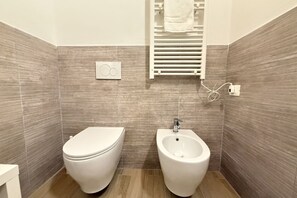 Ein Badezimmer mit Toilette, Bidet, Handtuchhalter und Steckdose.