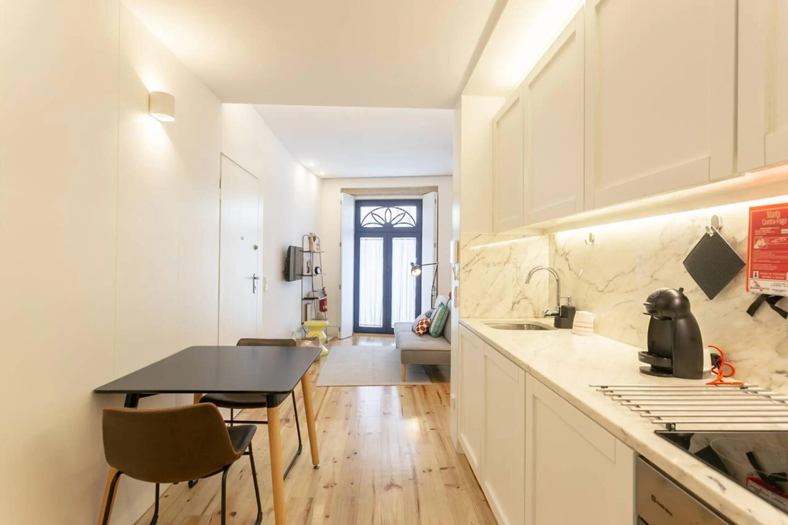 Una cucina compatta con zona pranzo, un piano di lavoro in marmo e un bollitore nero.