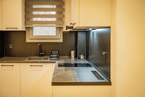 Eine moderne Küche mit eingebautem Herd, einem Spülbecken und einem Fenster mit Jalousien.