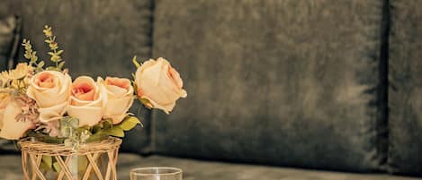 A round table with a glass of juice, a plate of grapes, and a vase with roses.
