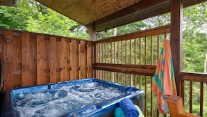 A hot tub with a wooden deck and a view of the forest. - Gorgeous log cabin that sleeps 7 with hot tub, firepit, exclusive hiking trails! (Sevierville)