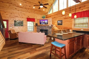 A cozy cabin interior with a wooden ceiling, a fireplace, a television, and a dining area. - Gorgeous log cabin that sleeps 7 with hot tub, firepit, exclusive hiking trails! (Sevierville)