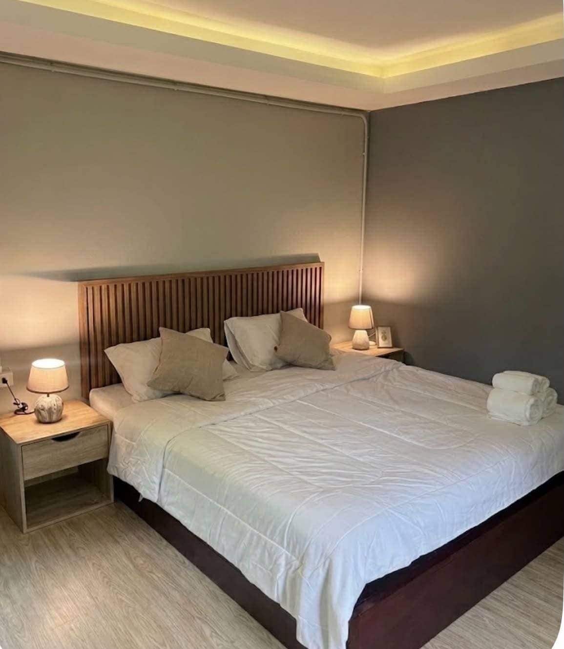 A hotel room with a large bed, two bedside tables, and a headboard.