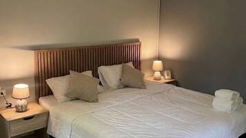 A hotel room with a large bed, two bedside tables, and a headboard.