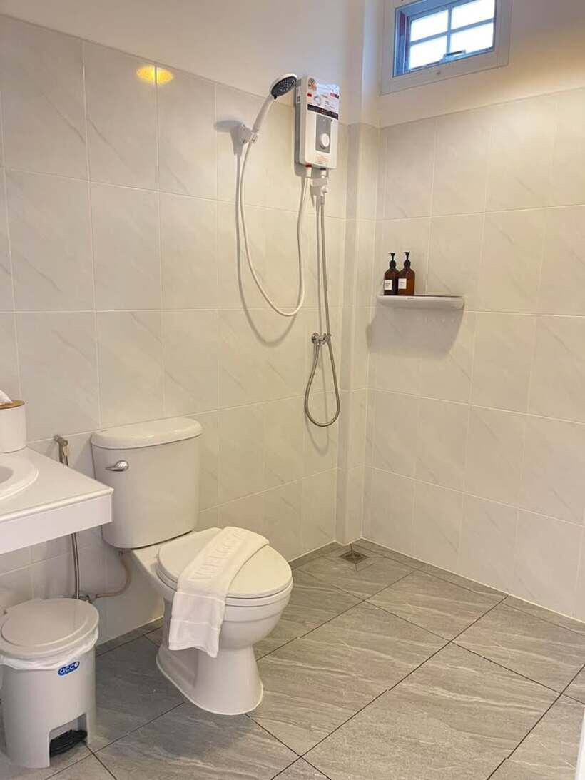 A bathroom with a toilet, a sink, a shower, and a window.