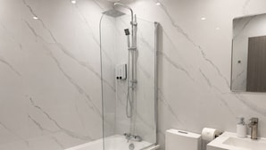 A modern bathroom with a glass-enclosed shower, a white toilet, and a marble-patterned wall. - Modern 2 Bedroom Serviced Apartment West Street Sheffield (Sheffield)