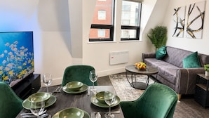 A modern living room with a dining area, a grey sofa, and a flat-screen TV. - Modern 2 Bedroom Serviced Apartment West Street Sheffield (Sheffield)