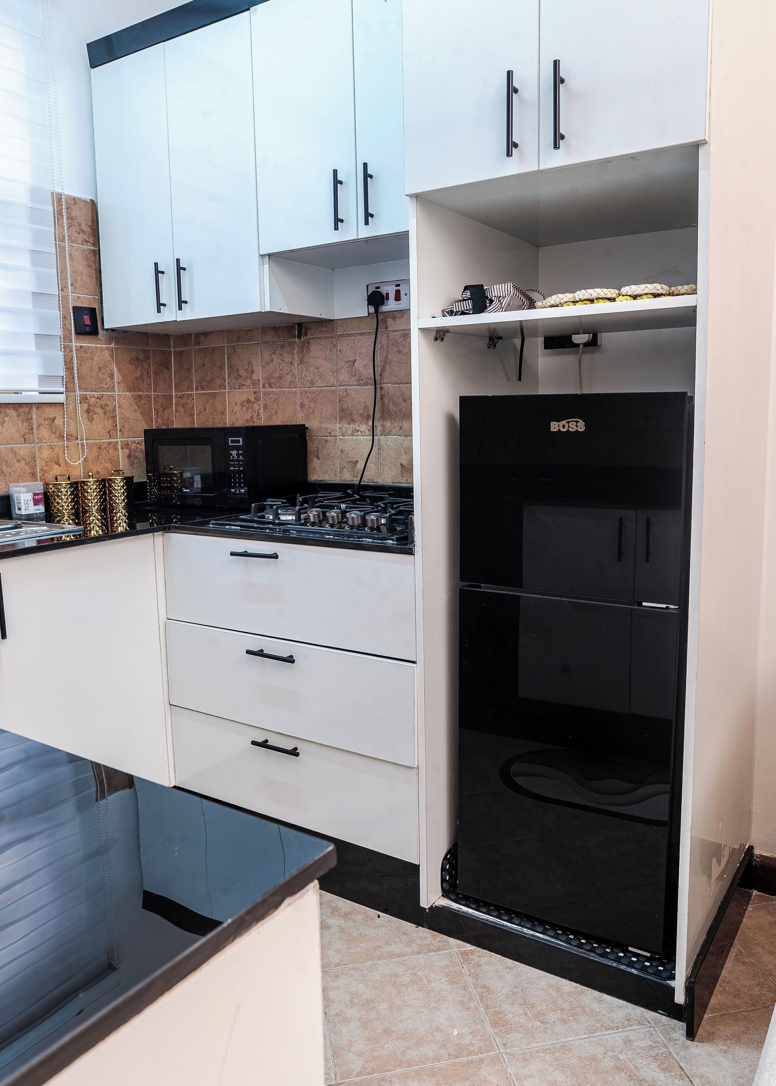 Una cocina con armarios blancos, una estufa negra y un refrigerador negro.