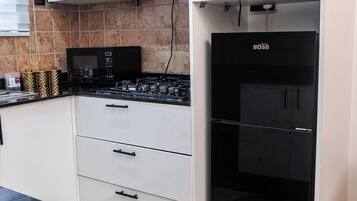 Una cocina con armarios blancos, una estufa negra y un refrigerador negro.