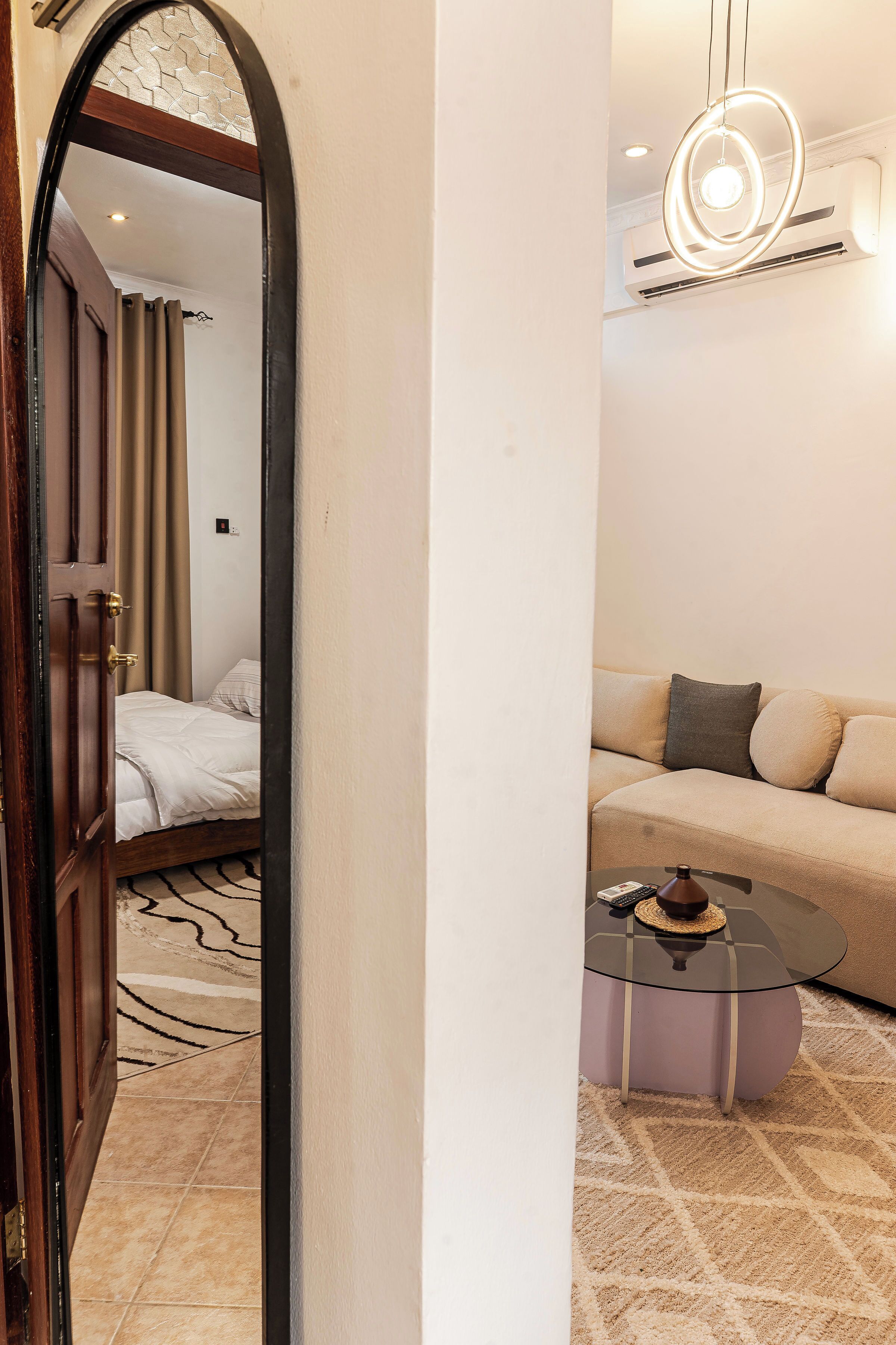 A hotel room with a bed, a sofa, a coffee table, and a modern light fixture.