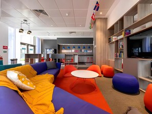 A modern lounge area with a sofa, ottomans, and a table. - Student Only Felda House Wembley (Wembley)