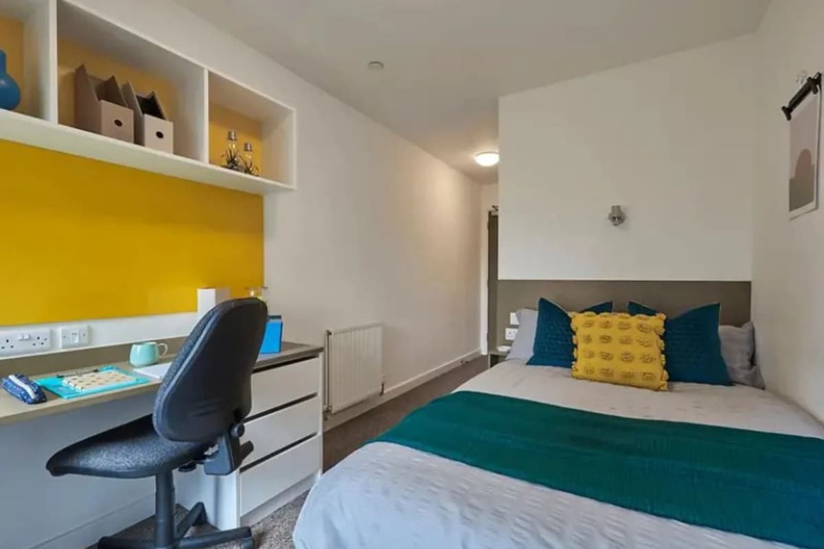 A bedroom with a bed, a desk, and a chair.