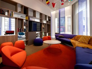 Ein modernes Wohnzimmer mit einer Couch, Poufs, einem Couchtisch und einem Bücherregal.