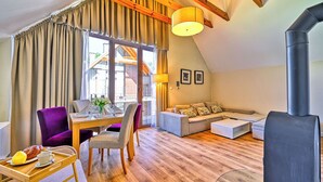 A modern living room with a dining area, wooden flooring, and a large window with curtains. - Apartamenty Sun & Snow Łomnica (Łomnica)
