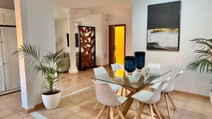 A modern dining area with a glass table and white chairs, a decorative wooden partition, and a painting on the wall. - Villa Chayofa (Chayofa)