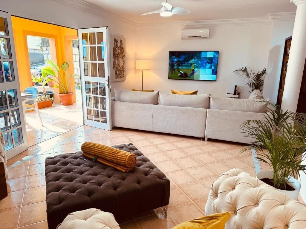 A living room with a sofa, ottoman, and a television.