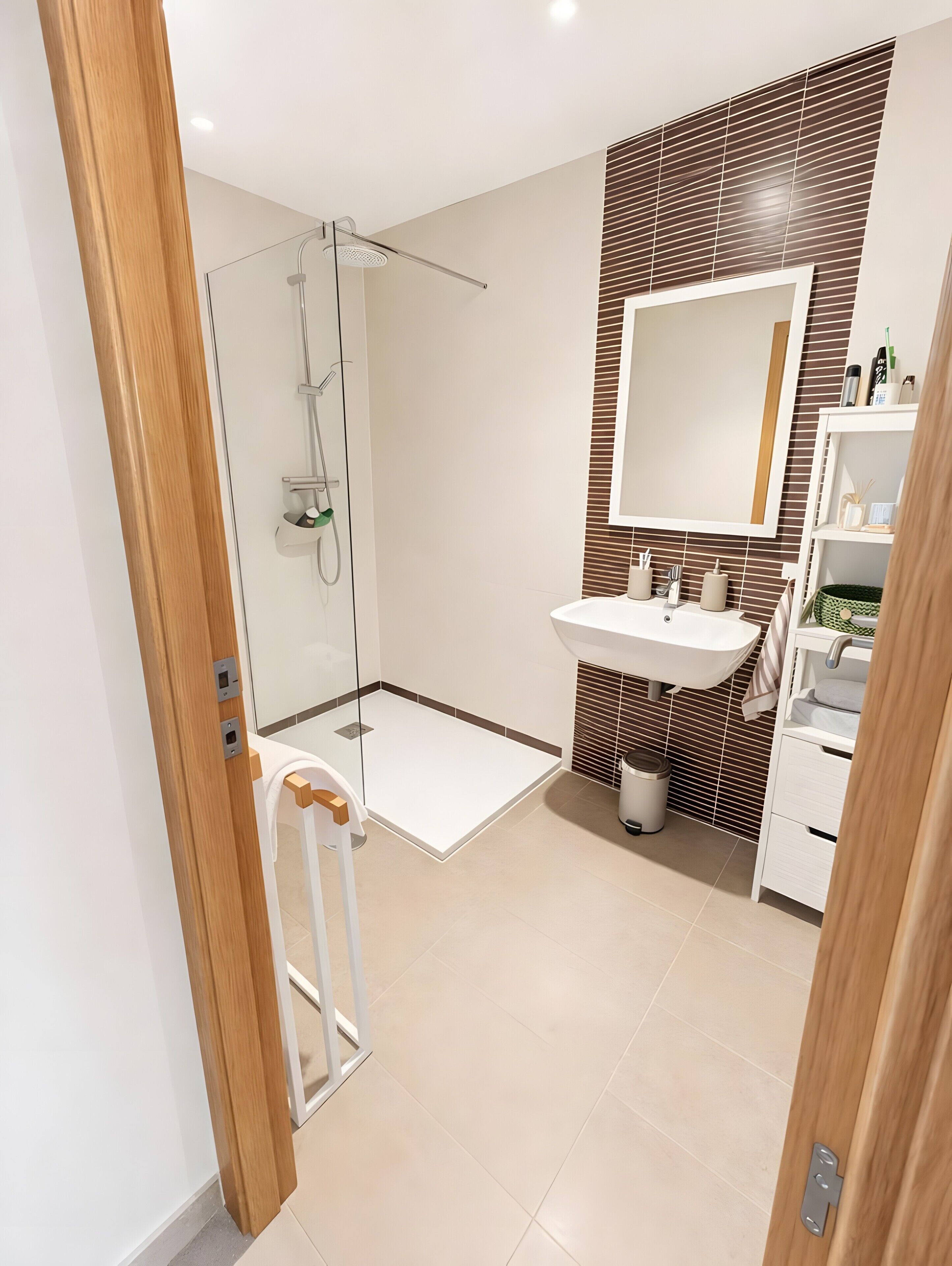 Une salle de bain moderne avec une douche à parois de verre, un lavabo avec un miroir et un sol carrelé.