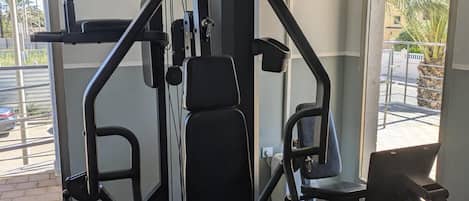 Una palestra dotata di diverse attrezzature per l'allenamento, tra cui una panca per squat, una pressa per pesi e macchinari per esercizi.