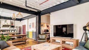 A modern living room with a large flat-screen TV, wooden furniture, and a red carpet. - Central City 2bed with Mountain Views Skywood Loft (Cape Town)