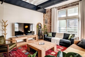 Ein modernes Wohnzimmer mit Fernseher, Couchtisch aus Holz und Sitzmöbeln.