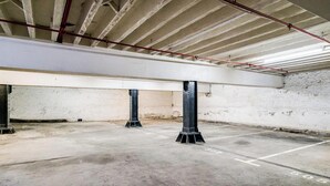 A spacious indoor parking area with concrete floors and metal pillars. - Central City 2bed with Mountain Views Skywood Loft (Cape Town)