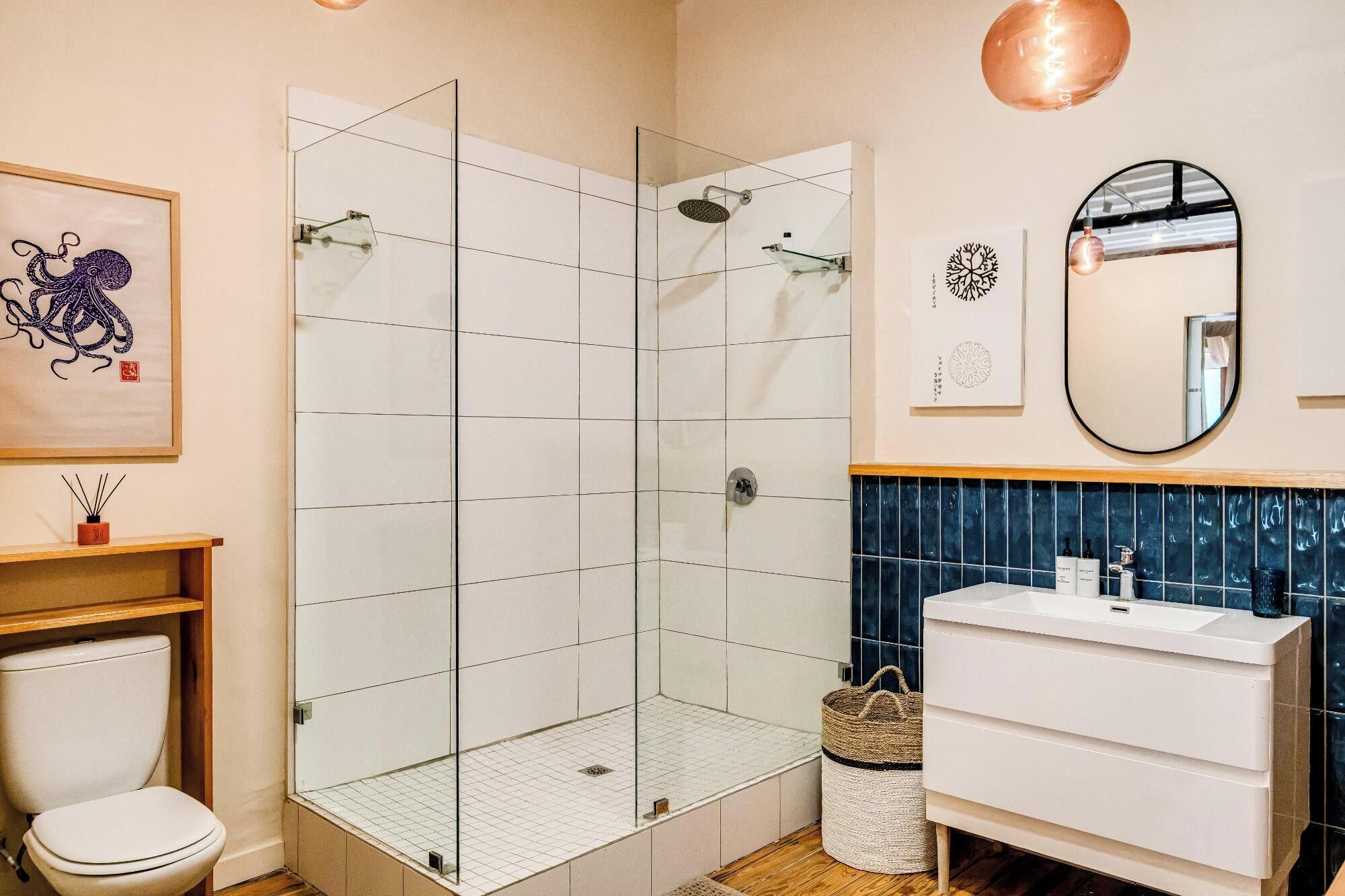 Een moderne badkamer met een douchecabine van glas, een wit wastafelmeubel en een spiegel.