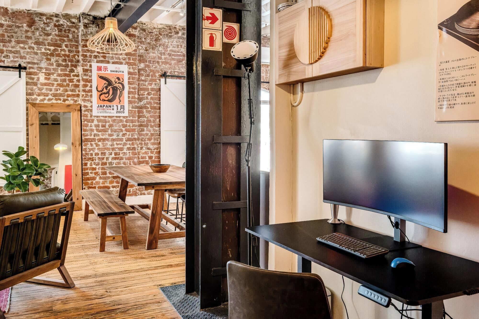 Un interior rústico con paredes de ladrillo visto, muebles de madera y un moderno espacio de escritorio.