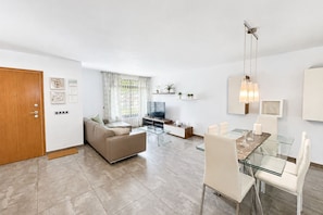 Ein modernes Wohnzimmer mit einer Couch, einem Fernseher, einem Glastisch und Stühlen.
