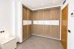 Ein Zimmer mit einem Holfschrank, einem weißen Nachttisch und einer Tür mit Griff.