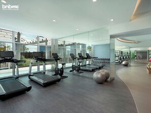 A modern gym with treadmills, exercise bikes, and free weights. - bnbme - Damac Majestine - 1BR (Dubai)
