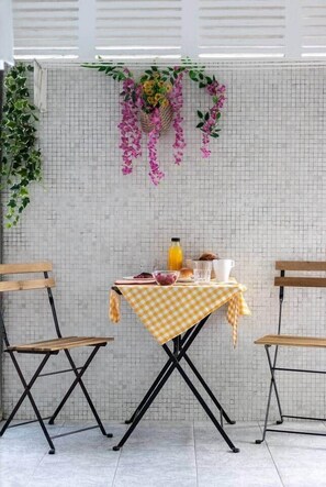 A dining area with a checkered tablecloth, two wooden chairs, and a table set with various items including a bottle, a bowl, and a cup. - POLITTE_Old Town vibes & parking (Bilbao)