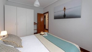 Habitació d'hotel amb un llit, un armari, un quadre i una làmpada penjant.