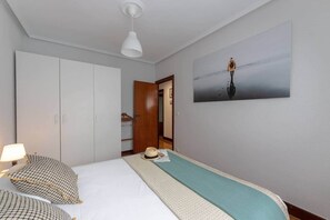 A hotel room with a bed, a wardrobe, a painting, and a hanging light fixture. - POLITTE_Old Town vibes & parking (Bilbao)