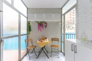 Ein kleiner Balkon mit Tisch, Stühlen und einer hängenden Pflanze.