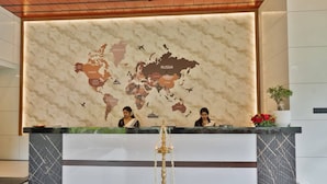 Un mostrador de recepción con un mural de un mapa mundial, una lámpara tradicional y una planta en maceta.