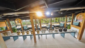 Un restaurante con una barra larga, varias zonas de estar y vistas a zonas verdes.