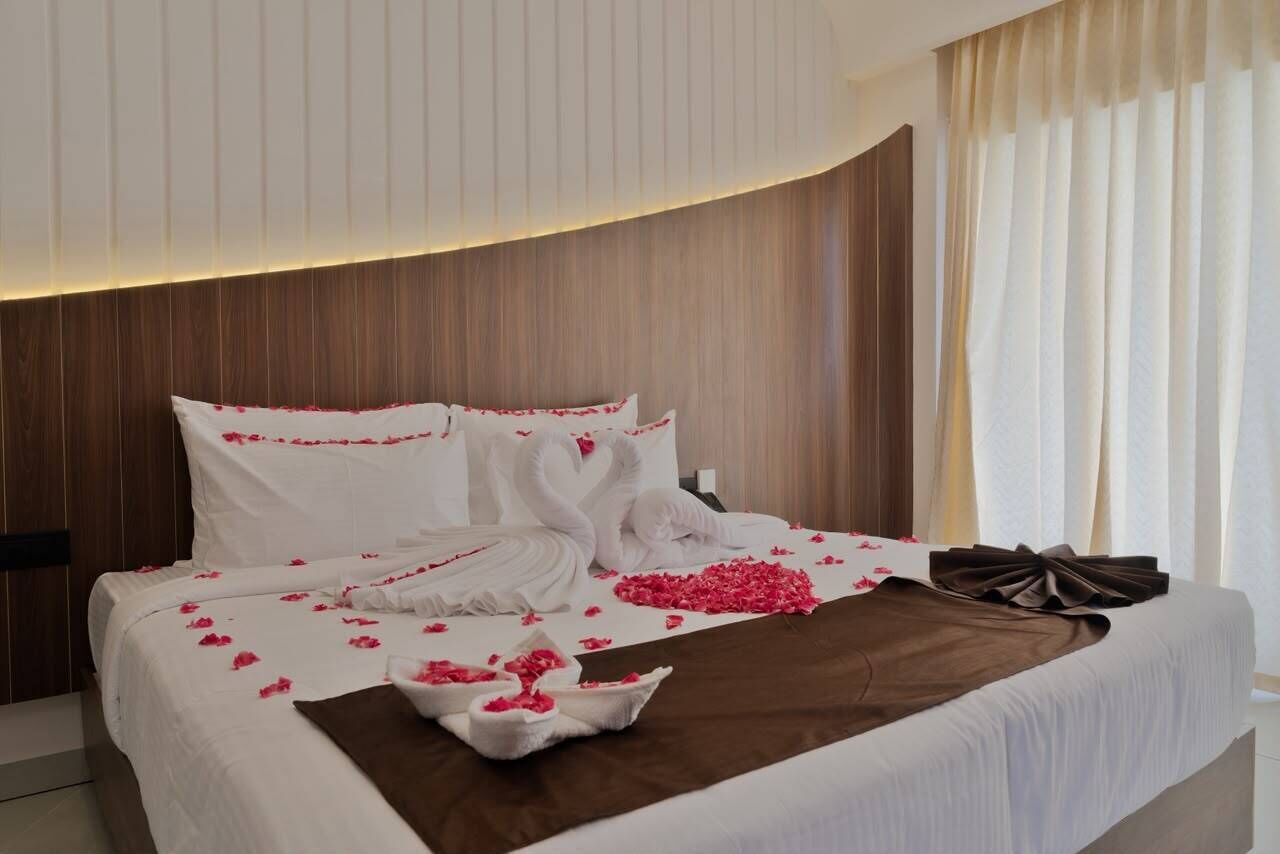 A hotel room with a bed, pillows, and a decorative arrangement of flowers and towels.
