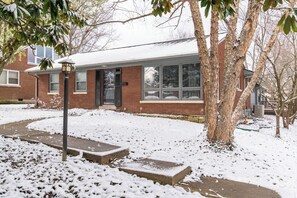 Ein Wohnhaus mit Ziegelaußenwand, einer Veranda und einem schneebedeckten Vorgarten.