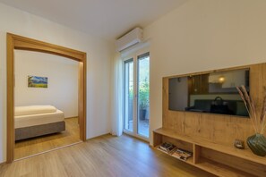 Un soggiorno moderno con un divano, una TV a schermo piatto e una libreria in legno.