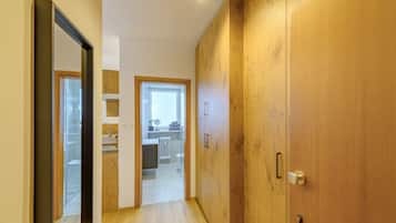 Ein Flur, der zu einem Badezimmer mit einem Holzschrank, einem Spiegel und einem Fenster führt.