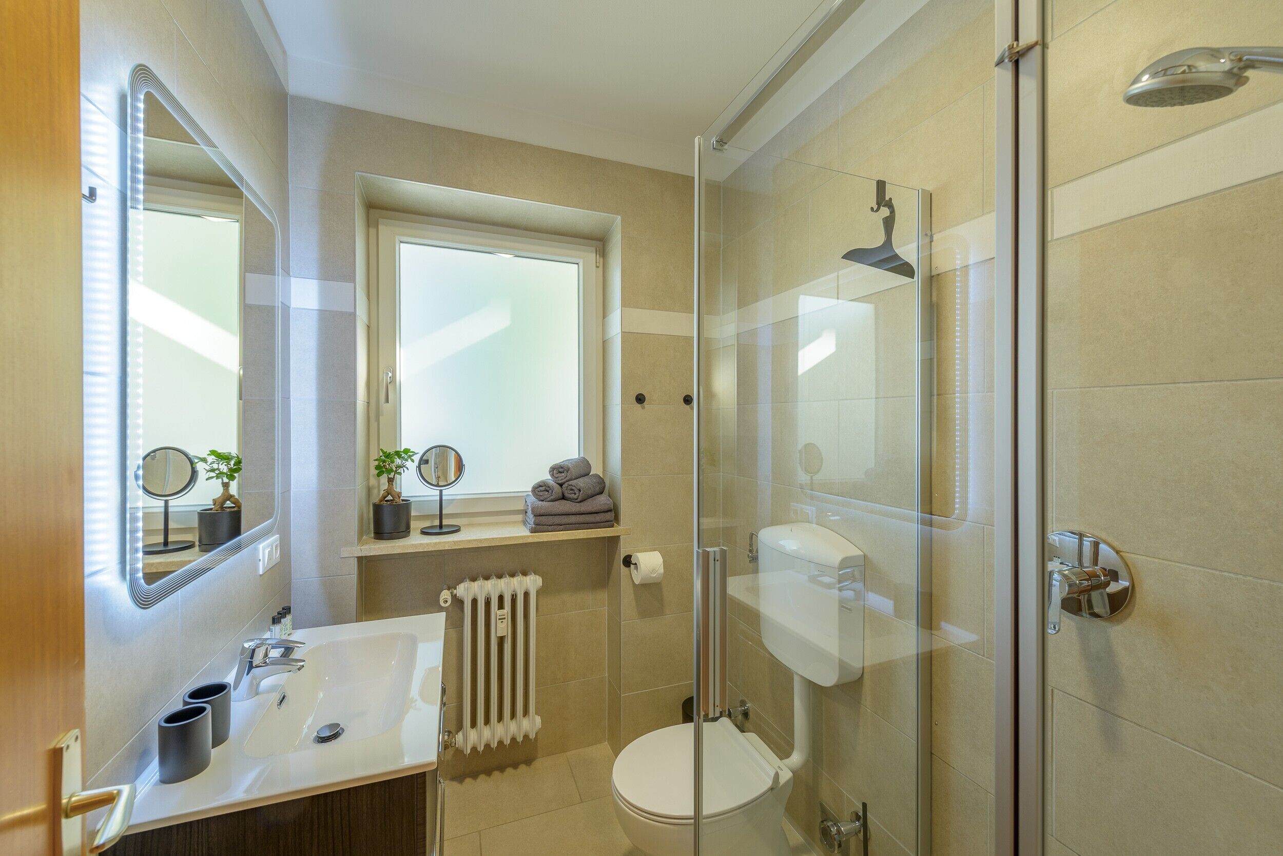 Ein modernes Badezimmer mit Duschkabine aus Glas, einem weißen Waschbecken und einer Toilette.