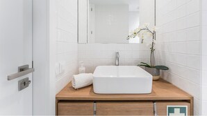 A bathroom with a white sink, a mirror, and a potted orchid. - Candy Crush: A Cozy Apartment in the Heart of Porto (Porto)