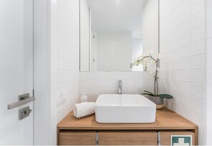 A bathroom with a white sink, a mirror, and a potted orchid. - Candy Crush: A Cozy Apartment in the Heart of Porto (Porto)