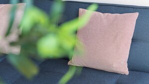 A sofa with a textured cushion and a plant in the foreground. - Candy Crush: A Cozy Apartment in the Heart of Porto (Porto)
